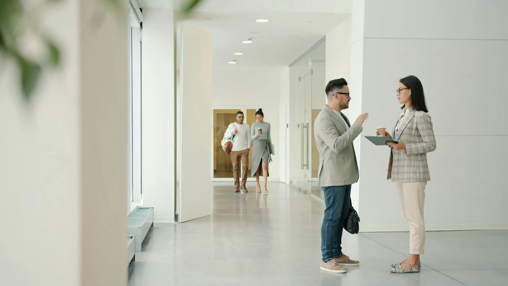 Two colleagues talking in a bright office corridor