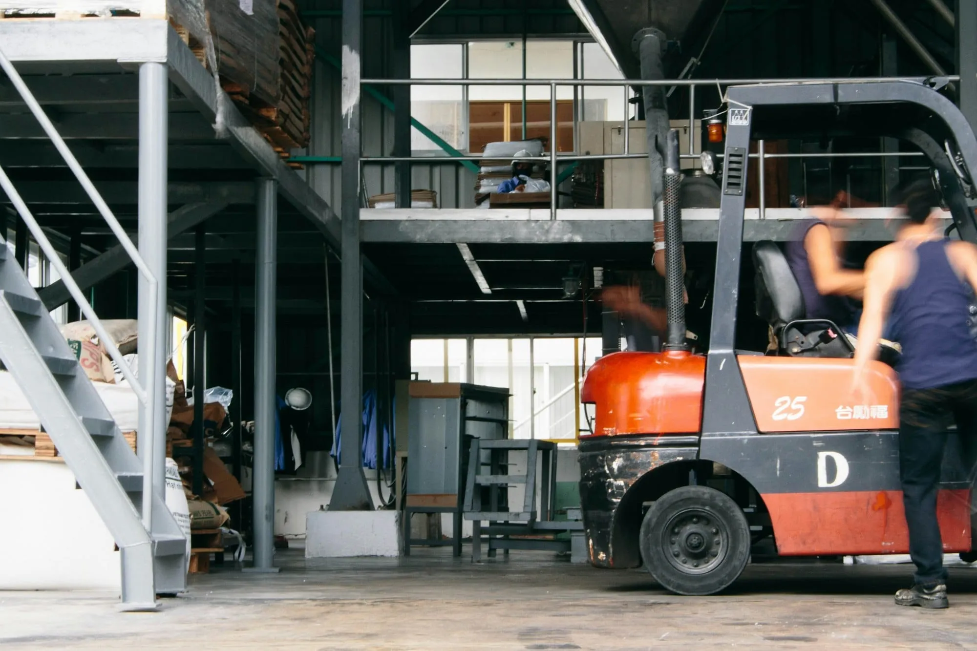 A forklift being driven through a warehouse, with stock and racking on either side.