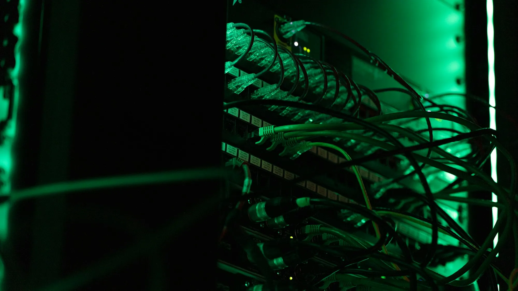 Network cabling in a server rack, lit green
