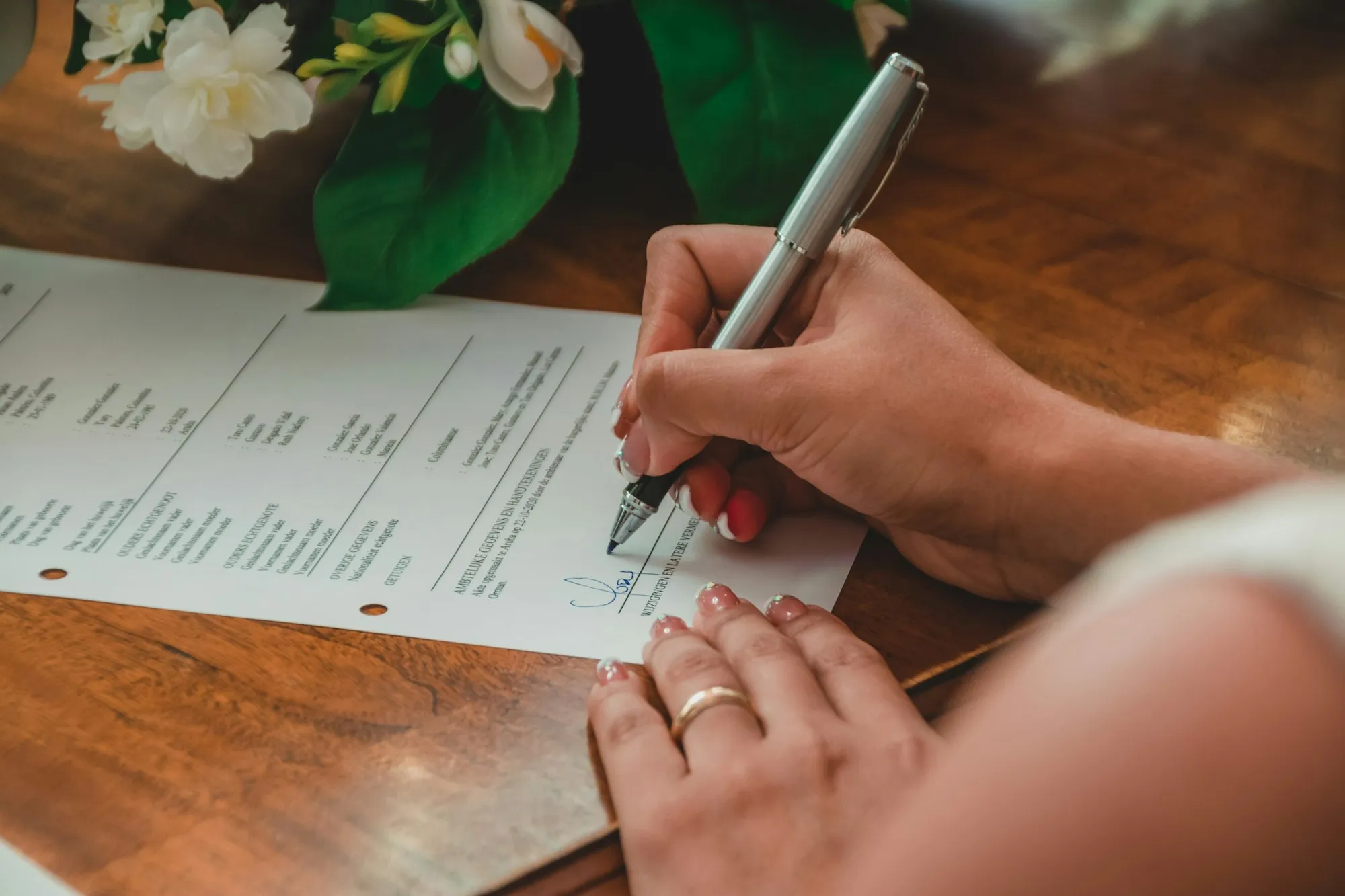 A hand signing a printed document with a fountain pen