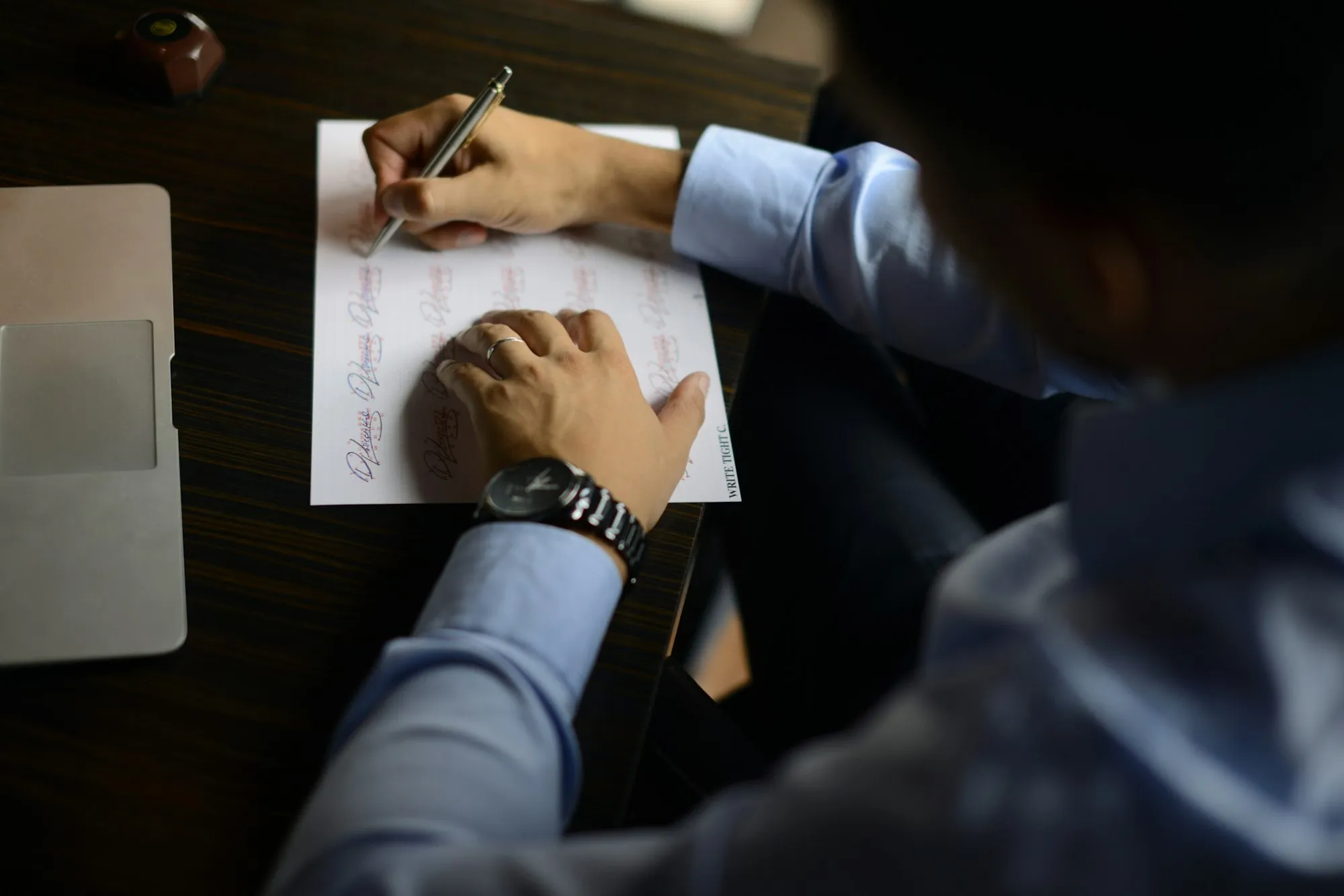 A person writing on a printed form at a desk